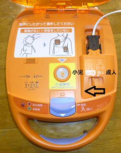 AED本体に小児モードと成人モードの切り替えボタンが搭載されていることを矢印と文字で説明している写真
