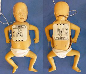 胸と背中の真ん中に電極パッドを張り付けられた赤ちゃんの人形の写真