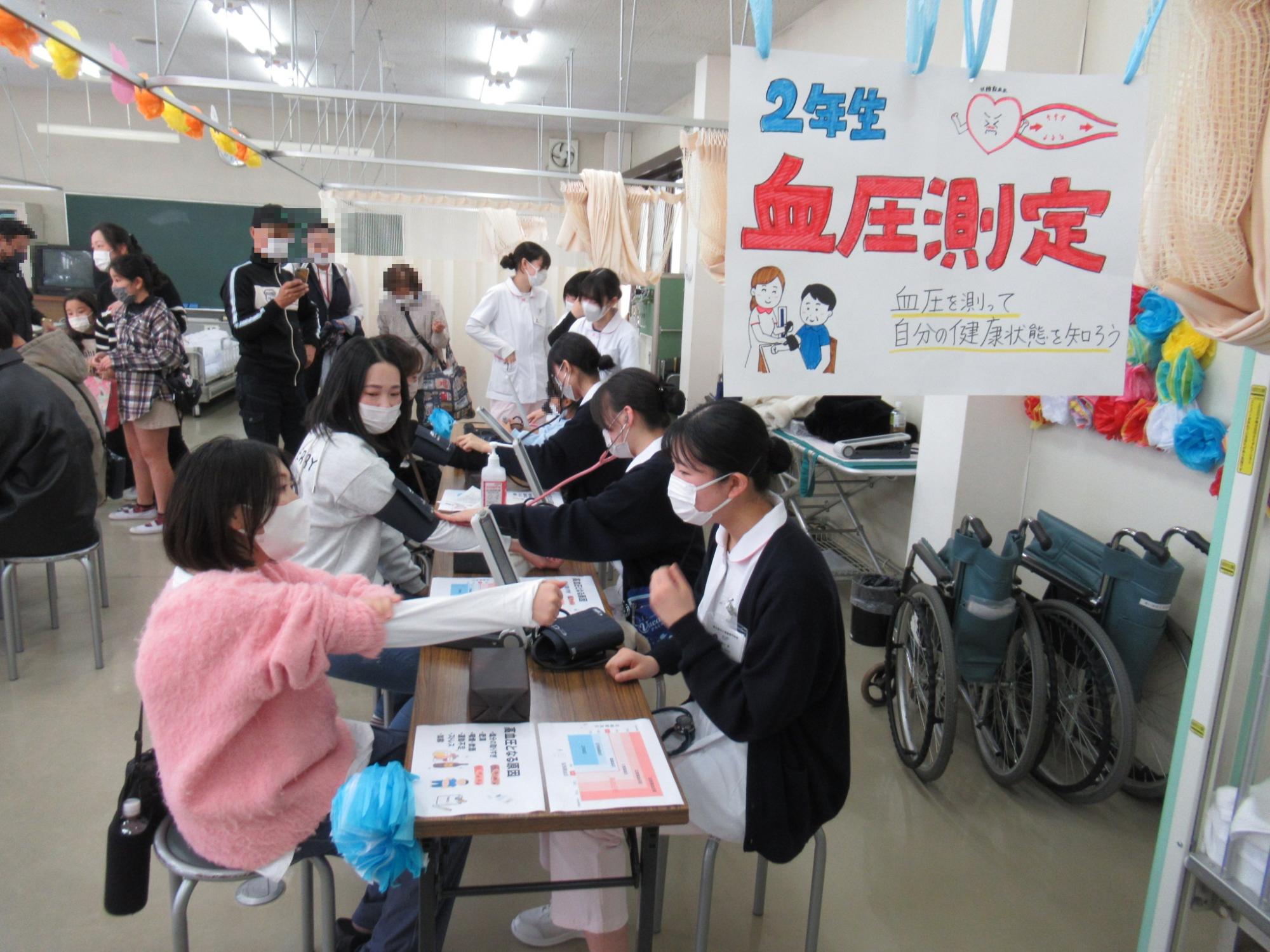 看護体験コーナーでは学生が血圧測定を行いました