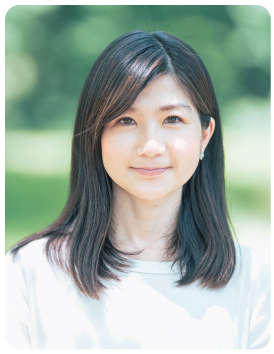白色の服に身を包み、笑顔をみせる井田寛子さんの写真