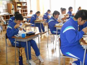 青いジャージを着て教室内で給食を食べている生徒の写真