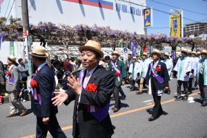 帽子をかぶったパレード参加者たちが練り歩いている様子を横から撮影した写真