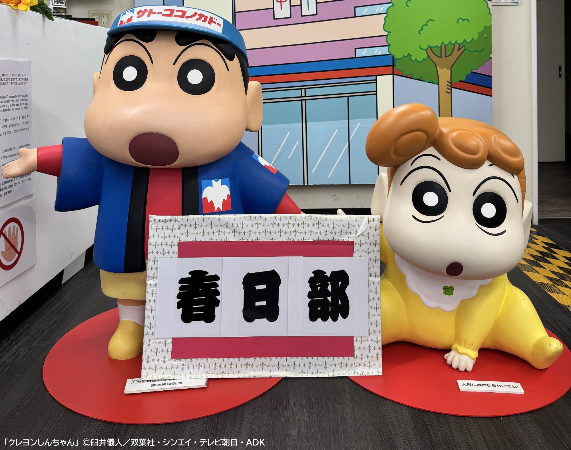 ぷらっとかすかべの店舗内に設置されている『クレヨンしんちゃん』の野原しんのすけくんとひまわりちゃんのモニュメントの写真。しんのすけくんは、作中に登場する「サトーココノカドー」の半被を着ている。