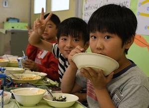 教室内で給食を食べている男子児童三名の写真