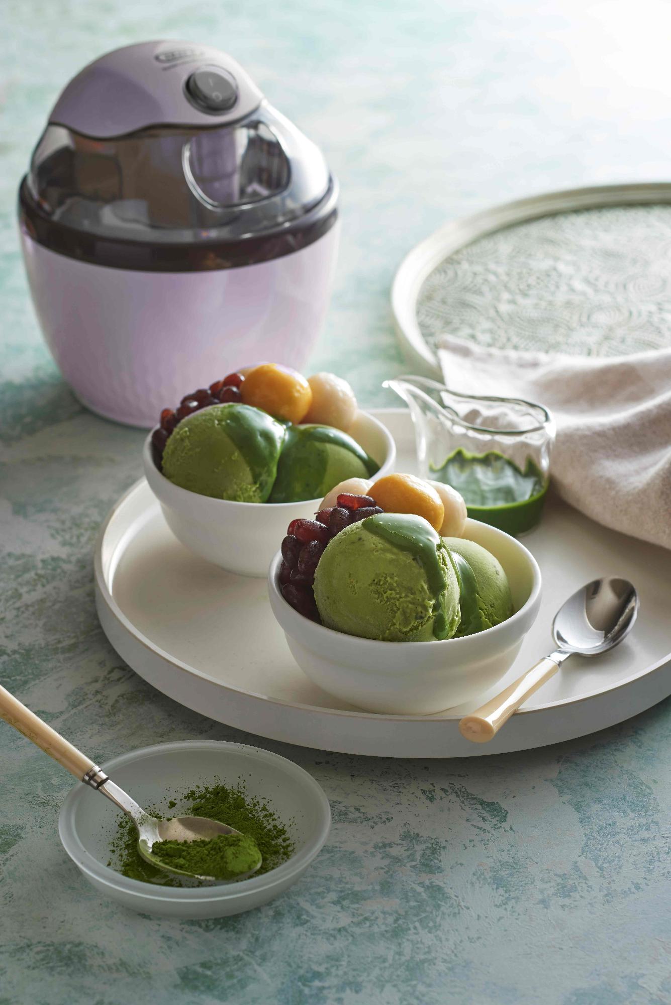 抹茶味のアイスと小豆、白玉が小皿に乗っている。小皿の後ろに薄ピンク色のアイスクリームメーカーが写った写真
