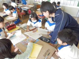教室でジャージを着て小学生に勉強を教えている中学生の写真