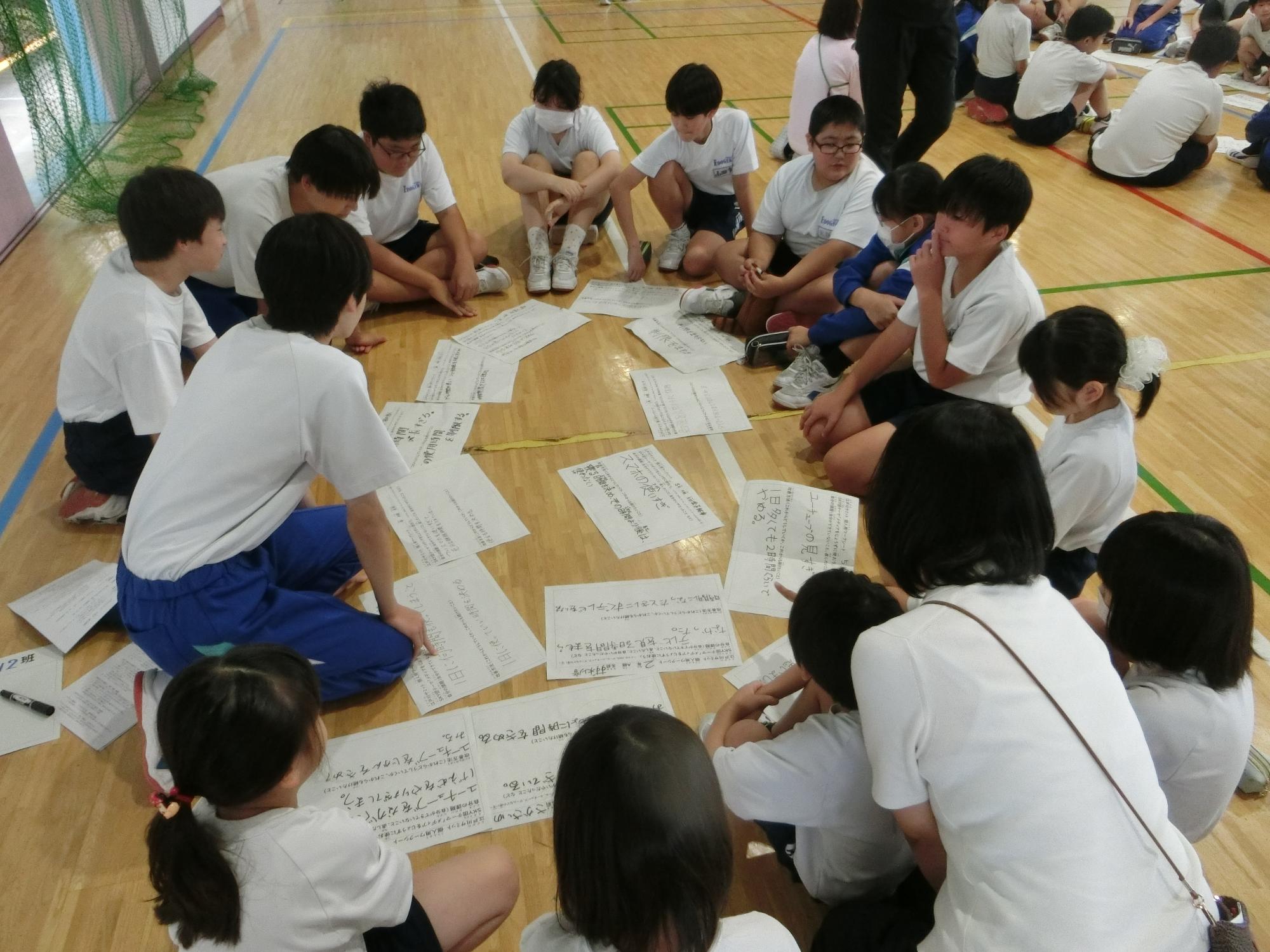 体育館で学年を超え、グループワークに取り組む児童・生徒たちの写真