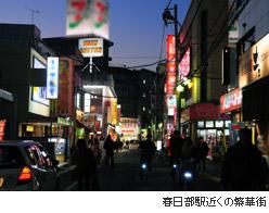 様々な色の看板が明るく光っている繁華街の写真に、春日部駅近くの繁華街と説明書きされている写真