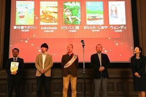 日本タウン誌・フリーペーパー大賞2019の授賞式で登壇して並んでいる5人の写真