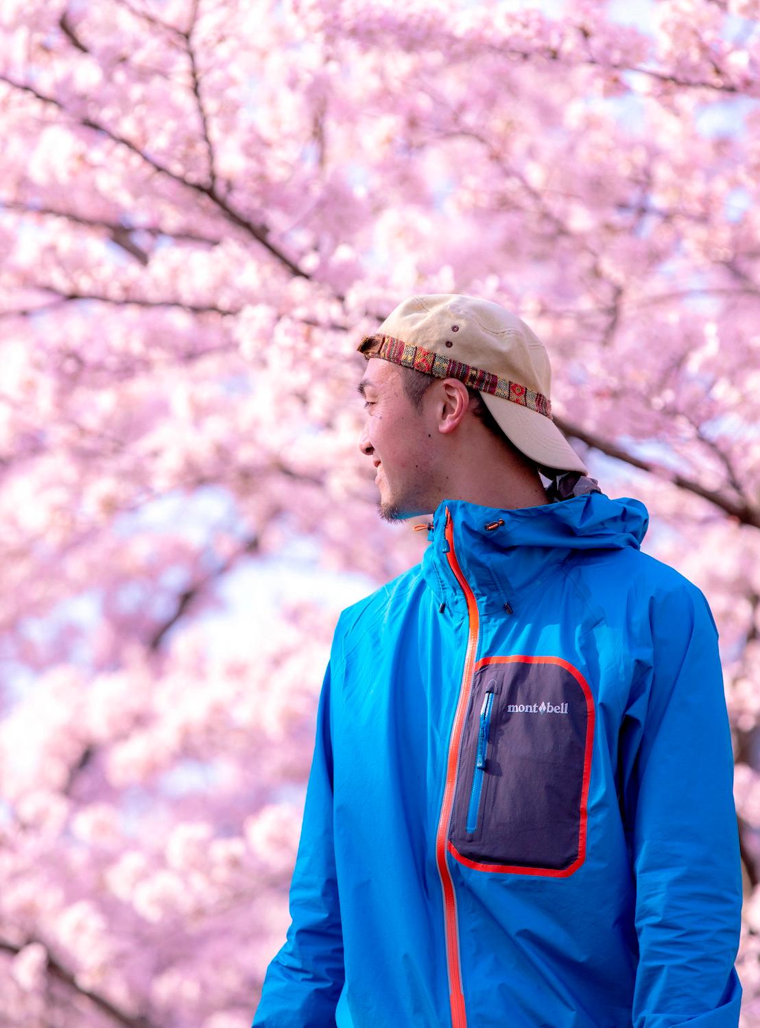 桜を背景にたそがれるカメラ講座の講師梶直輝さん