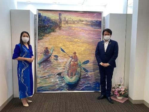 大歳古利根川が描かれた大きな絵画の前で、大久保信子さんと岩谷市長が並んで立っている写真です。