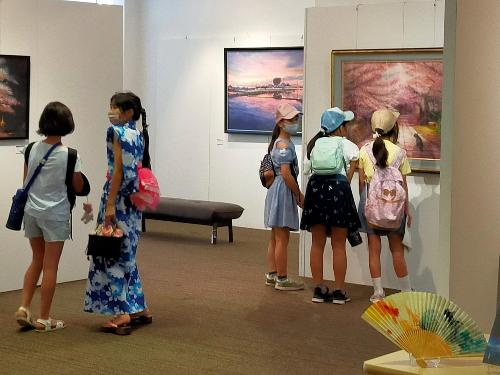 5人の女の子たちが、絵画を興味深く見ている様子です。