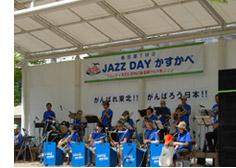 青いTシャツ姿でステージの上に立ち、楽器を奏でる演奏者たちの写真