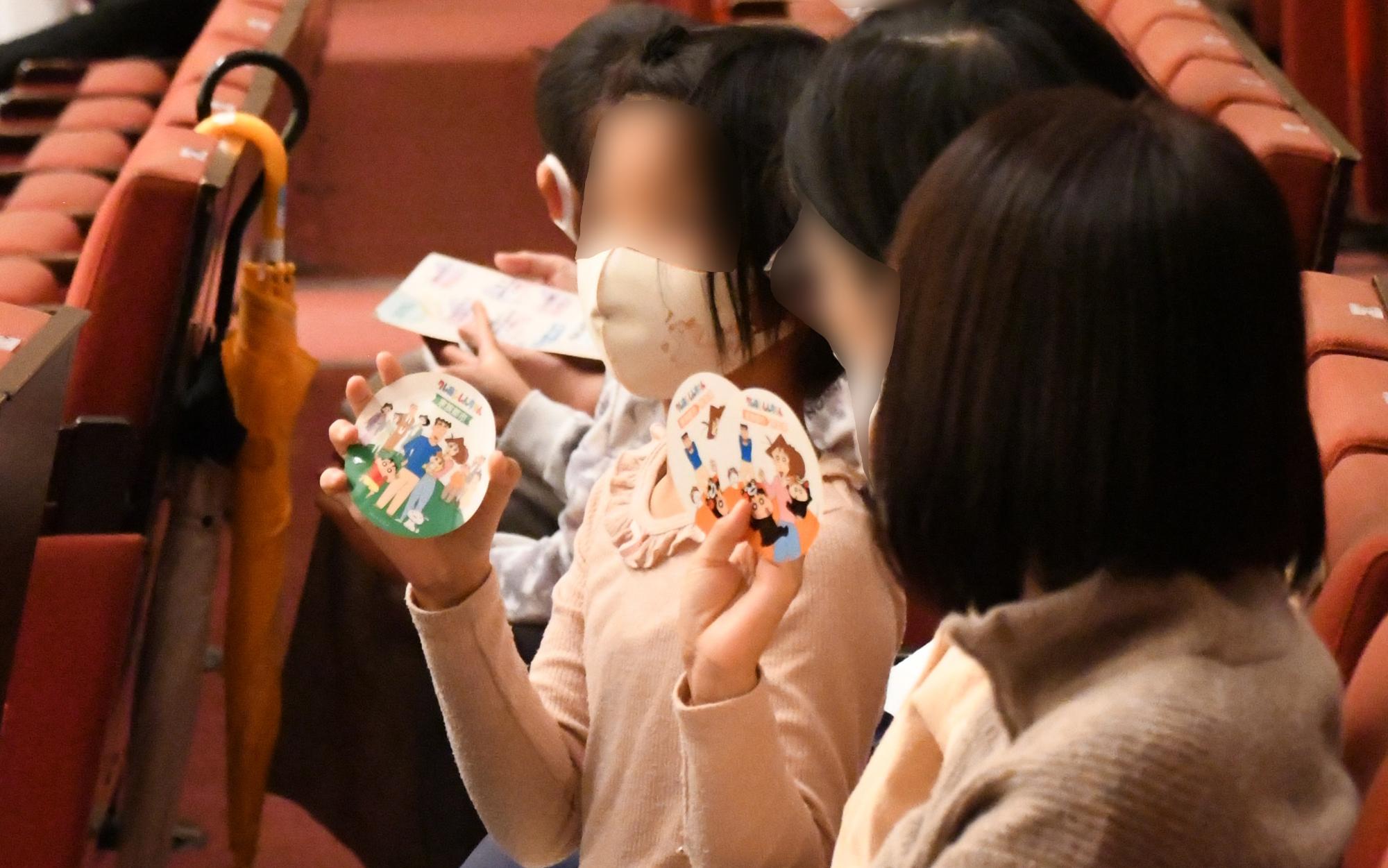 クレヨンしんちゃんのステッカーを手に持つ子どもの写真
