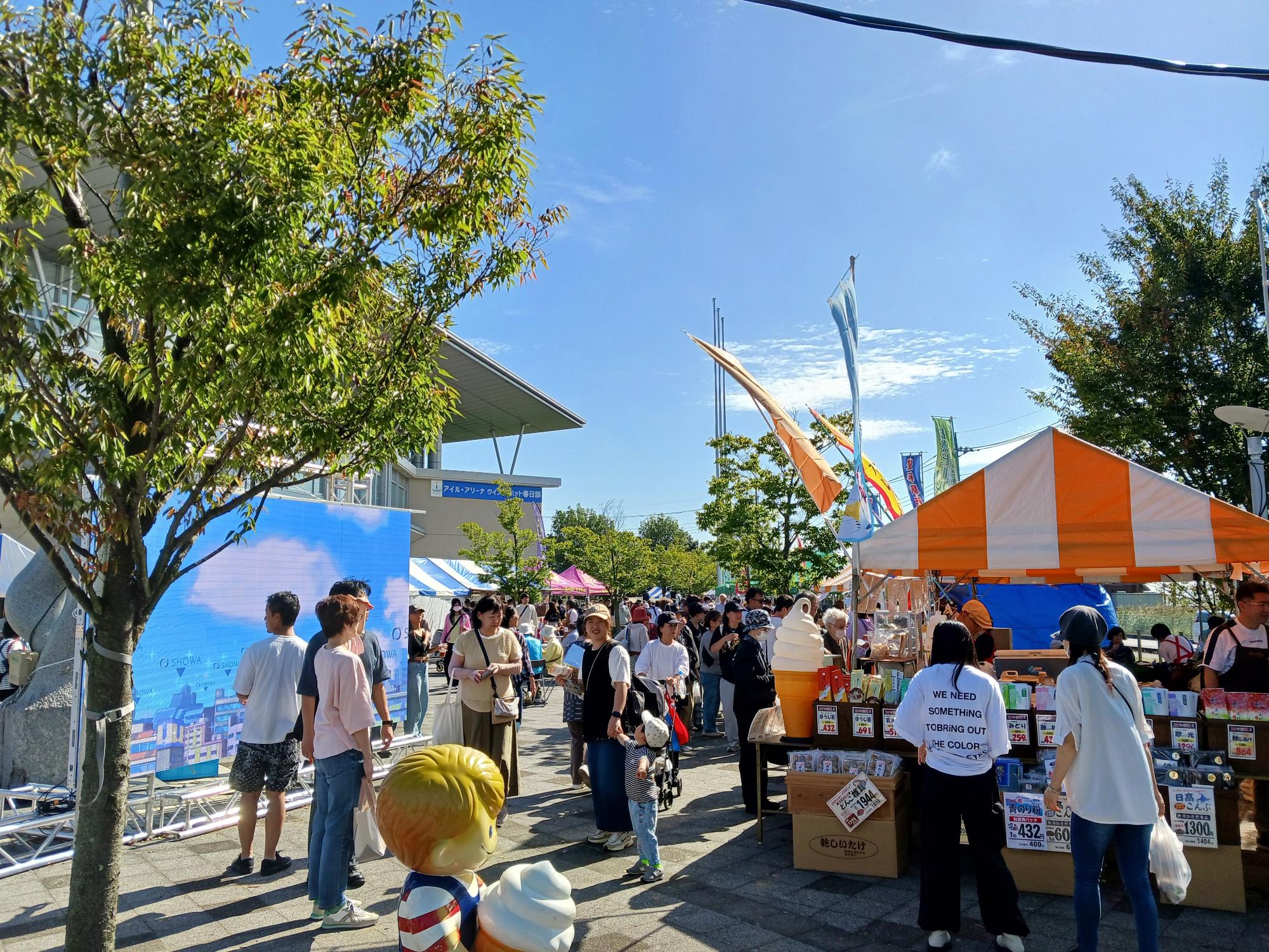 屋外に様々な色ののぼりが立っていて、多くの人が集まっている写真