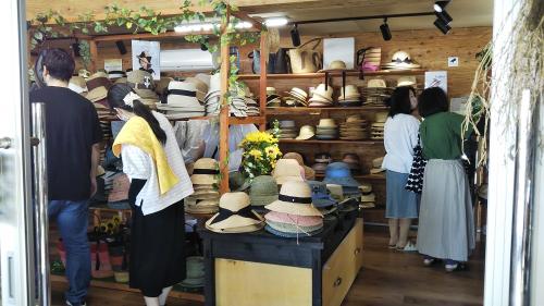 店内にはさまざまな形の麦わら帽子が陳列され、お客さんが商品を選んでいます。