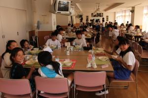 ランチルームでテーブルを囲み給食を楽しむ児童たちの写真