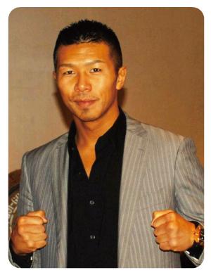グレーのジャケットと黒いワイシャツを着た内山 高志さんの写真