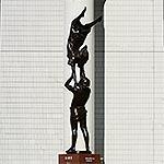 下で支える男性の肩に手を乗せ倒立する女性の銅像の写真