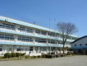 雲ひとつない青空の下、水色のラインが入った3階建ての学校校舎の写真
