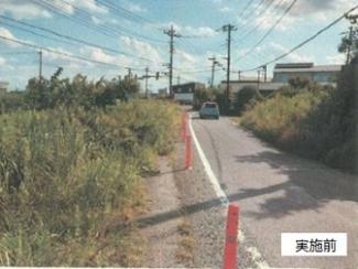 幸松小学校通学路の外側線に沿ってポールが設置されているカーブの道の写真