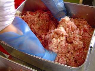 玉ねぎや桜エビなどの具材が入ったひき肉を大きい容器で混ぜている写真