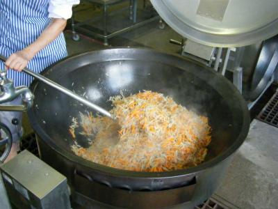 大鍋で野菜を炒めている写真