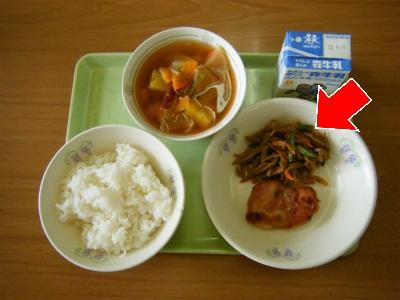 お盆に載せられた給食の五目きんぴらのお皿を矢印で示した写真