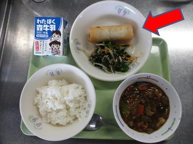 お盆に載せられた給食の春巻きのお皿を矢印で示した写真