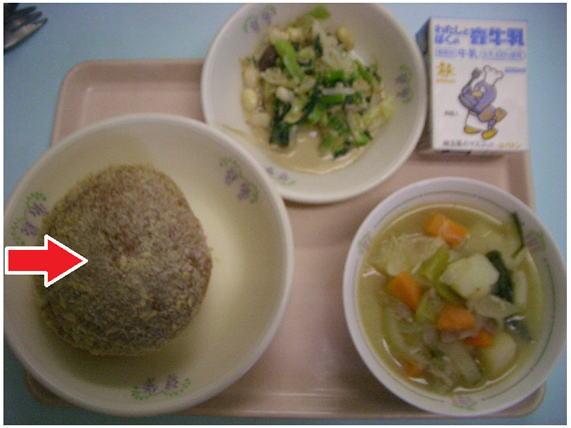 おぼんに載せられた給食の焼きカレーパンのお皿を矢印で示した写真