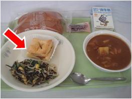 お盆に載せられた給食のココアパイのお皿を矢印で示した写真