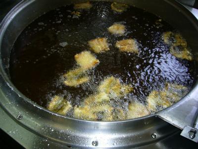 大きな鍋できつね色に揚がっている様子のかば焼きの写真