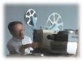 男性が映写機に手を当てて機器を操作している写真
