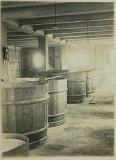 蔵に酒樽が並んで置かれている幸松酒造工場の白黒写真