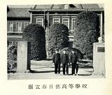 門の前に学生服を着て並ぶ生徒が写された県立春日部高等学校の白黒写真