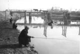 川のほとりで釣り人が佇む白黒写真
