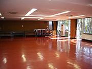 フローリングの床が外の光を反射する内牧地区公民館大会議室の写真