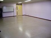 ピンク色の壁と木製フローリングの床が特徴的な豊春第二公民館第二会議室の写真