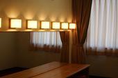 行燈風の照明と鏡とが壁一面に並び備え付けられている庄和南公民館楽屋の写真