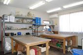 木製の作業机と完成品を展示する棚などが備えつけられている庄和南公民館創作室1の写真