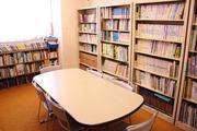 白いテーブルと白い本棚のある藤塚公民館図書室の写真