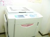 部屋の角に白い印刷機が置かれている庄和南公民館印刷室の写真