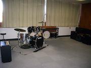 灰色のブロックマットの上にドラムが用意されている内牧地区公民館会議室兼リハーサル室の写真