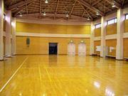 寄木張りフローリングの床が照明の光を反射する内牧地区公民館体育室の写真
