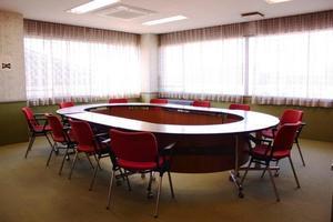 ドーナツ型の机の周りに赤い椅子が並ぶ豊野地区公民館会議室の写真
